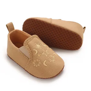 Detailansicht khakifarbener Baby-Lauflernschuhe mit goldener Stern- und Mondstickerei.