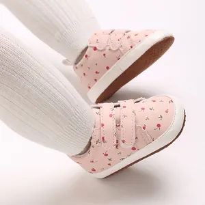 Nahaufnahme von rosa Baby-Lauflernschuhen mit Kirschmuster und Klettverschluss