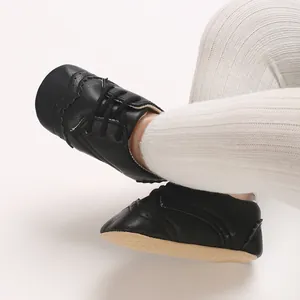 Vue détaillée de chaussures bébé noires à semelle souple et leggings blancs.