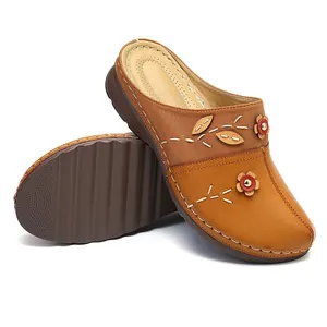 Women's tan wedge clogs with floral accents and decorative white stitching details