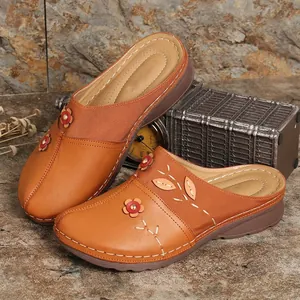 Vintage tan women's wedge mules with floral applique and elegant white stitching details.