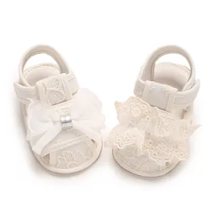 Detailansicht von weißen Baby-Sandalen aus Spitze mit eleganter Netzschleife