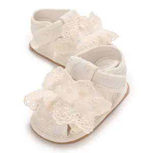 Detailansicht weißer Babysandalen mit zarter Spitze und Blumenverzierung