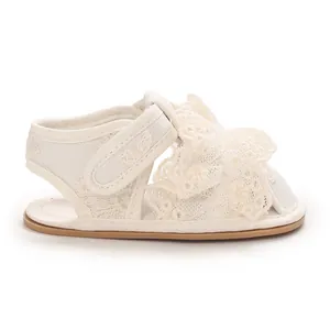 Seitenansicht weißer Baby-Sandalen mit Spitze und rutschfester Gummisohle für Mädchen.