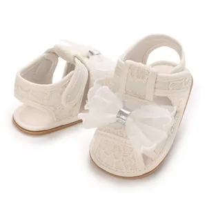 Detailaufnahme cremeweiße Baby-Sandalen für Mädchen mit Spitze und großer Netzschleife.