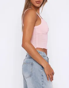 Side view detail of a pink twisted bust camisole crop top with spaghetti straps and rib-knit fabric.