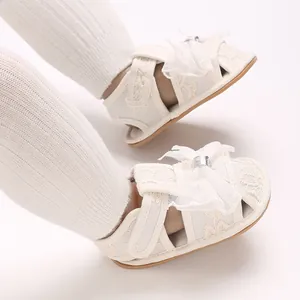Detailaufnahme von weißen Lauflernsandalen für Babymädchen mit zarten Spitzenschleifen
