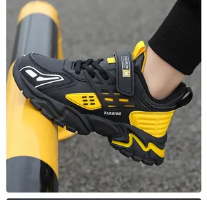 Vue rapprochée des baskets de course légères en cuir noir et jaune pour garçons.