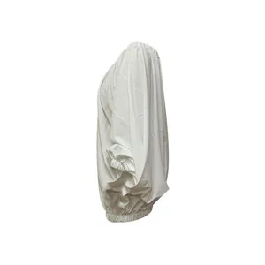 Side view detail of white batwing sleeve dress featuring elastic cuffs and hem