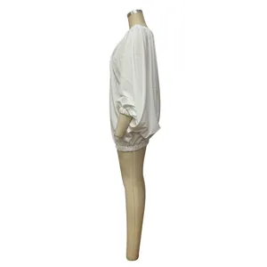 Detailed side view of a white oversized batwing sleeve dress shown on a professional mannequin