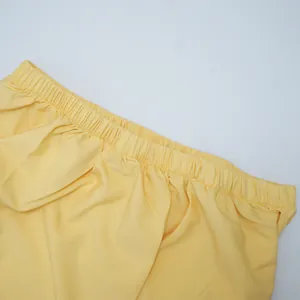 Close-up detail of the elastic pleated waistband on a light yellow summer dress.