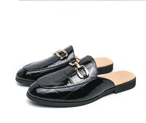 Close-up view of black crocodile embossed men's mules loafers with polished gold chain buckle