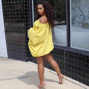 Outdoor street style shot of a woman in a yellow off-shoulder batwing sleeve dress