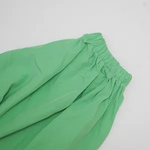 Close-up detail of the elastic gathered waistband on a light green summer dress fabric