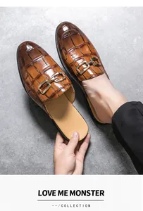 Detailed view of men's brown crocodile patterned backless loafers with gold buckle.