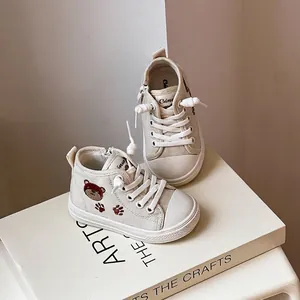 Dettaglio delle sneakers in tela alte beige per neonati con simpatico orso ricamato.
