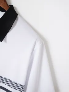 Close-up view of a white polo shirt featuring a black collar and fine pique fabric texture