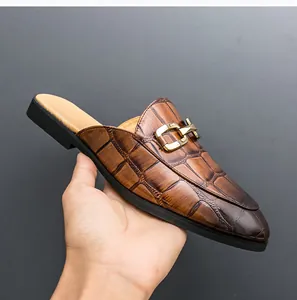Macro detail shot of brown crocodile textured men's fashion mule with golden buckle