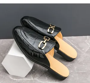 Detailed macro shot of black croc-embossed men's backless loafers with gold metal buckle