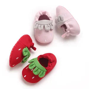 Detalle de primer plano de lindos zapatos de piso para bebés con tema de fresa en rojo y rosa