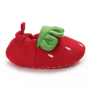 Vista lateral de un lindo zapato de bebé con forma de fresa roja y hojas verdes
