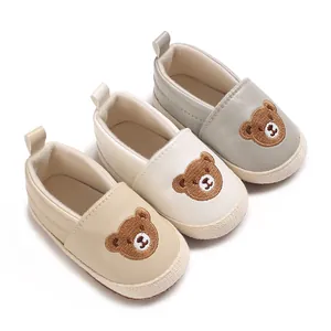 Detalle de zapatos de gateo para bebé con bordado de oso en tres suaves colores pastel.