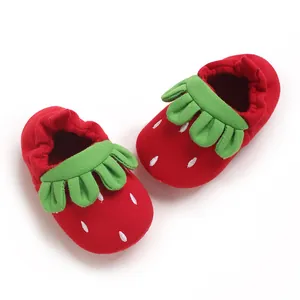 Detalle de zapatos de bebé fresa con suela blanda y cuello de hojas verdes suaves.