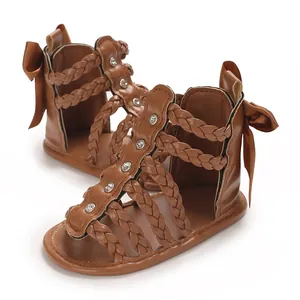 Detailansicht der braunen Kleinkindsandalen mit geflochtenen Riemen und einer Schleife