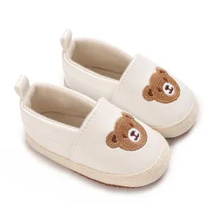 Primer plano de zapatos de bebé blancos para caminar con bordado de oso pardo muy tierno y suave.