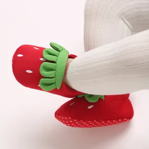 Primer plano detallado de lindos zapatos de suela blanda para bebé con diseño de fresa roja