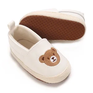 Primer plano de zapatos de bebé con bordado de oso y detalle de suelas antideslizantes