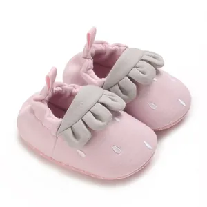 Vista detallada de zapatos rosa para bebé con suela blanda y detalles de volantes grises
