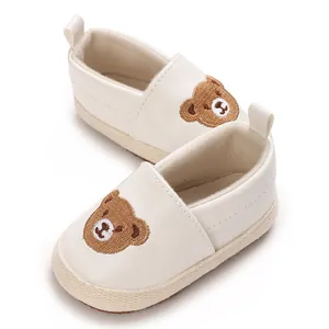 Detalle de zapatos de gateo blancos para bebé con bordado de oso marrón