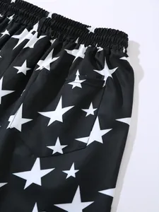 Close-up detail of black men's beach shorts with white star pattern and elastic waist.
