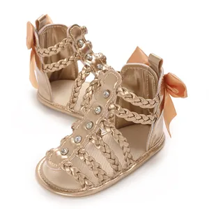 Nahaufnahme goldener Babysandalen mit geflochtenen Riemen und elegantem Schleifendetail