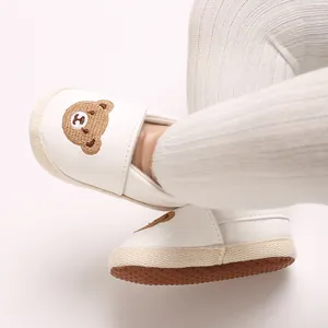 Primer plano de zapato de bebé blanco con un bordado de oso y una suela antideslizante
