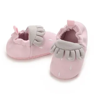 Vista detallada de zapatos suaves para bebé con diseño de fresa rosa y volantes grises.