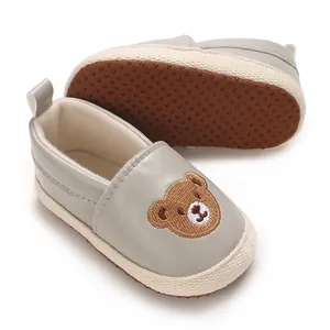 Detalle de zapatos grises para bebés con un diseño de oso bordado muy adorable