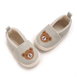 Primer plano detallado de zapatos grises para bebé con bordado de un tierno osito