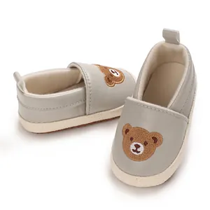 Vista detallada de zapatos de bebé grises con un lindo bordado de oso en la parte superior.