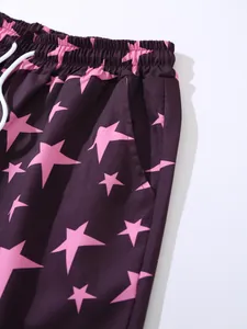 Close-up detail of men's beach shorts with pink star pattern and white drawstring waistband.