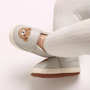 Primer plano de zapatos de bebé grises para caminar con lindo patrón de oso bordado