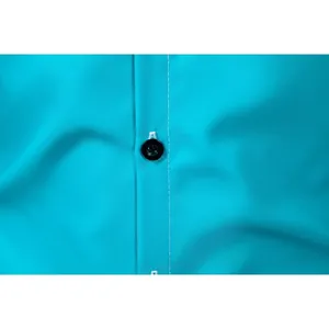 Macro view of white stitching and black button on a turquoise men's business shirt