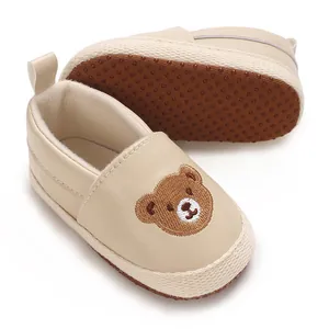 Primer plano de zapatos para bebé beige con un motivo de oso bordado artesanal