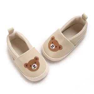 Vista detallada de zapatos de bebé beige con un lindo diseño bordado de oso pardo en el frente