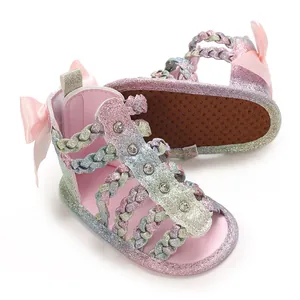 Detailansicht glitzernder geflochtener Babysandalen mit rosa Schleife und weicher Sohle