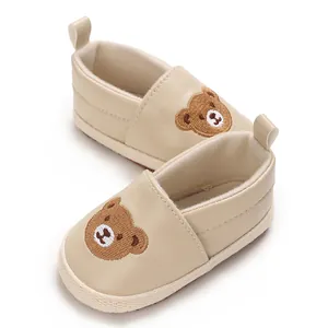 Vista detallada de zapatos de bebé beige con un bonito motivo de oso bordado para caminar.