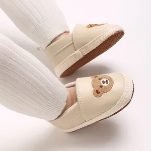 Detalle de zapatos beige para caminar de bebé con lindo bordado de oso de dibujos