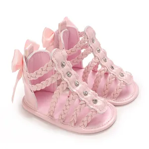 Nahaufnahme von rosa Babysandalen mit geflochtenen Riemen und glänzenden Strassakzenten