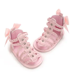 Detail der rosa Babysandalen mit geflochtenen Riemen, Strasssteinen und Schleife.